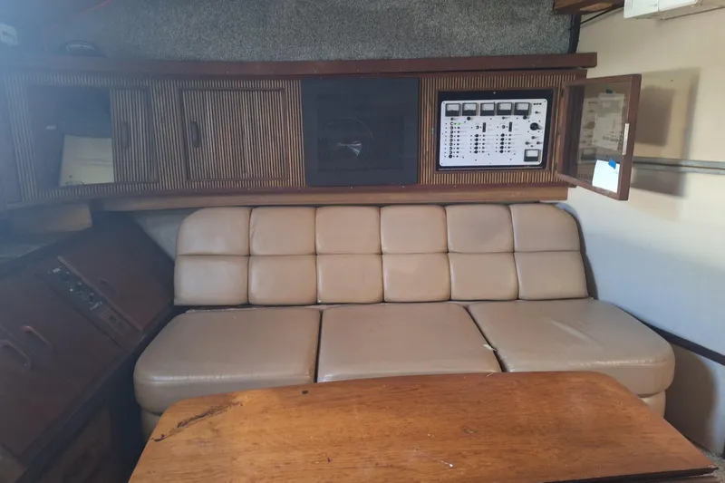 Slide: The Image of 1985 Sea Ray 390 Express Cruiser interior with beige seating and wooden cabinetry. - 22