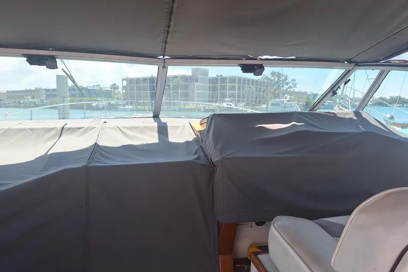 Slide: The Image of 1985 Sea Ray 390 Express Cruiser interior with covered dashboard and marina view. - 25