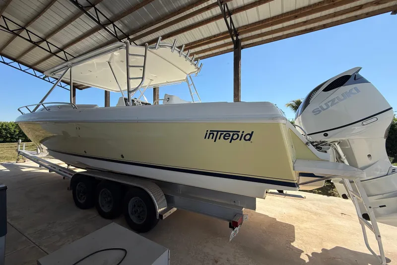 The Image of 2008 Intrepid 377 Walkaround boat on trailer under shelter, featuring Suzuki outboard engines. - 0