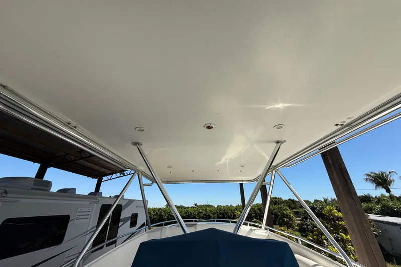 Slide: The Image of 2008 Intrepid 377 Walkaround boat canopy with support poles, surrounded by greenery. - 110