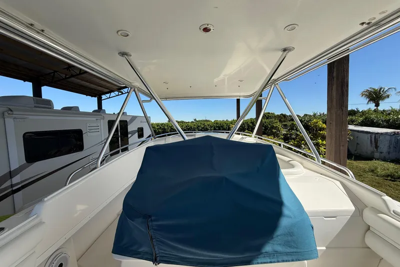 Slide: The Image of 2008 Intrepid 377 Walkaround boat with blue cover, parked near RVs and greenery. - 111