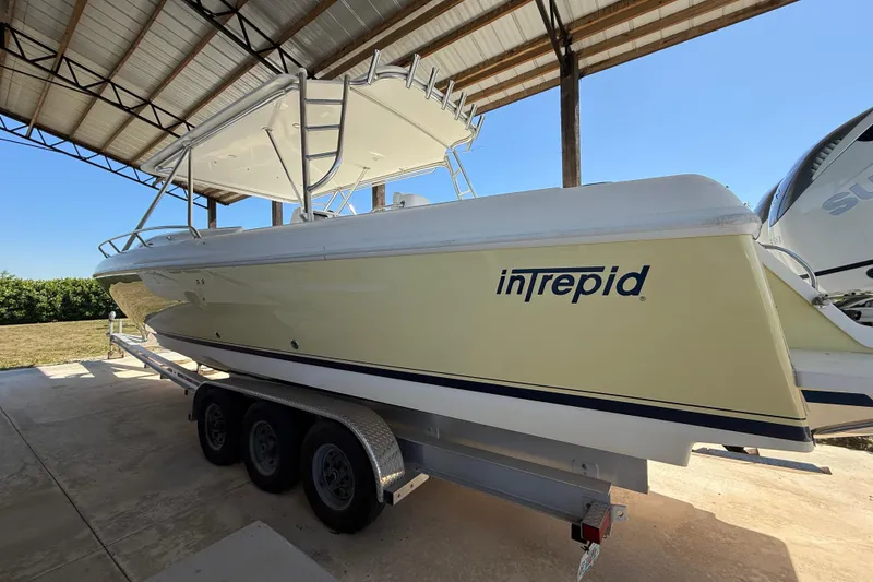 Slide: The Image of 2008 Intrepid 377 Walkaround boat on trailer under a metal roof. - 15