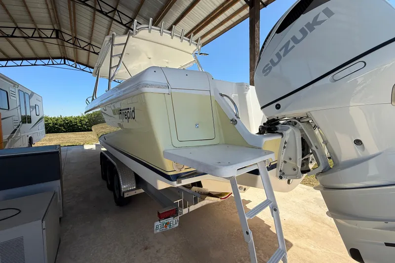 Slide: The Image of 2008 Intrepid 377 Walkaround boat with Suzuki engine, parked under a metal roof. - 23