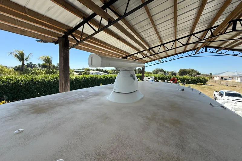 Slide: The Image of 2008 Intrepid 377 Walkaround boat under a metal canopy, surrounded by greenery. - 60
