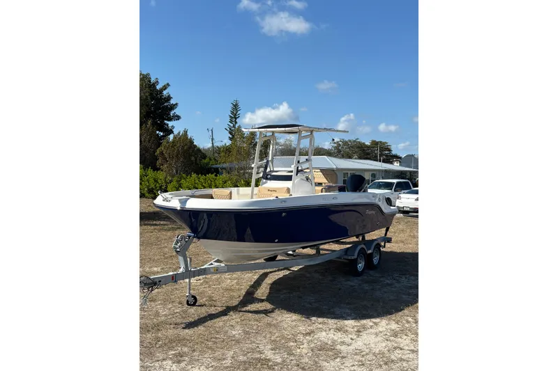 Slide: The Image of 2026 Bayliner Trophy T22CC boat on trailer, parked outdoors under blue sky. - 12