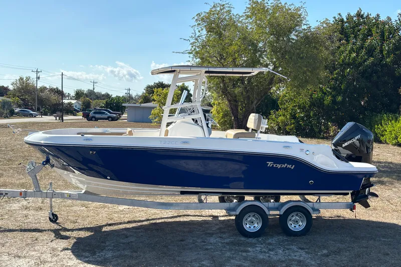 Slide: The Image of 2026 Bayliner Trophy T22CC boat on trailer, parked outdoors, side view. - 13