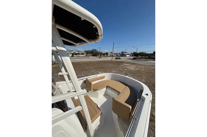 Slide: The Image of 2026 Bayliner Trophy T22CC boat with tan seating and T-top, parked on land. - 18
