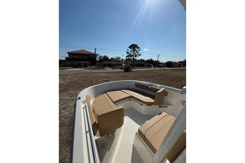 Slide: The Image of 2026 Bayliner Trophy T22CC boat with tan seating, parked outdoors under clear sky. - 19