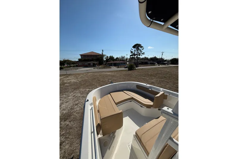 Slide: The Image of 2026 Bayliner Trophy T22CC boat with tan seating, parked on dry land under clear blue sky. - 20