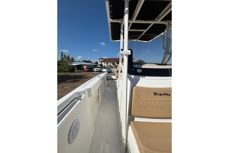Slide: The Image of 2026 Bayliner Trophy T22CC boat with tan seating and sleek design under clear blue sky. - 22