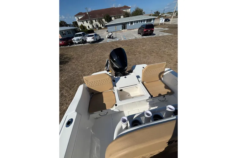 Slide: The Image of 2026 Bayliner Trophy T22CC boat interior with seating and motor, parked outdoors. - 28