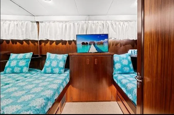 Slide: The Image of 1989 Hatteras 70 Motor Yacht cabin with twin beds, TV, and turquoise bedding. - 23