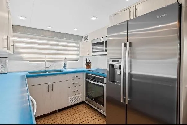 Slide: The Image of Modern kitchen in 1989 Hatteras 70 Motor Yacht with stainless steel appliances and blue countertops. - 9