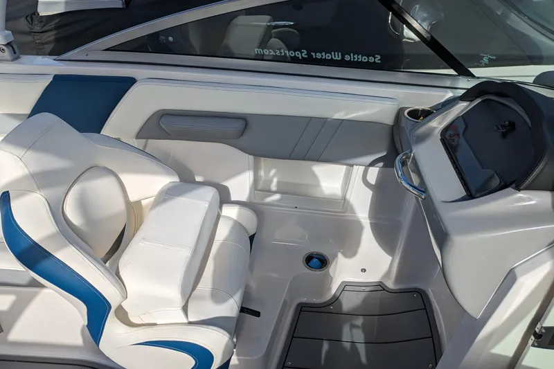 Slide: The Image of 2023 Chaparral 23 Surf boat interior with white and blue seating and dashboard. - 5