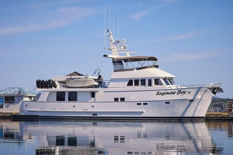 Slide: The Image of Luxury Northern Marine 75 yacht, 2000 model, named "Saginaw Bay" docked on calm water. - 3