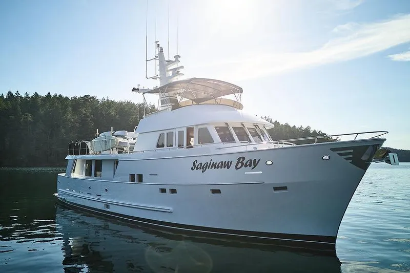 Slide: The Image of Northern Marine 75 yacht from 2000, named "Saginaw Bay," on calm water with forested background. - 75