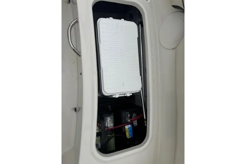 Slide: The Image of 2023 Stingray 182 SC boat storage compartment with battery and white cover. - 16