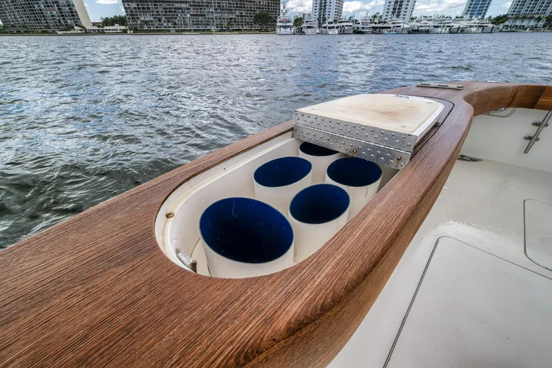 Slide: The Image of 2012 Viking 70 Enclosed Bridge yacht with rod holders and cutting board, docked by waterfront buildings. - 32