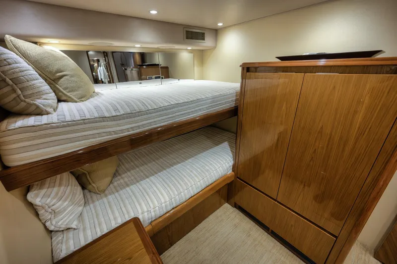 Slide: The Image of Interior of 2012 Viking 70 Enclosed Bridge yacht with cozy bunk beds and wooden cabinetry. - 90