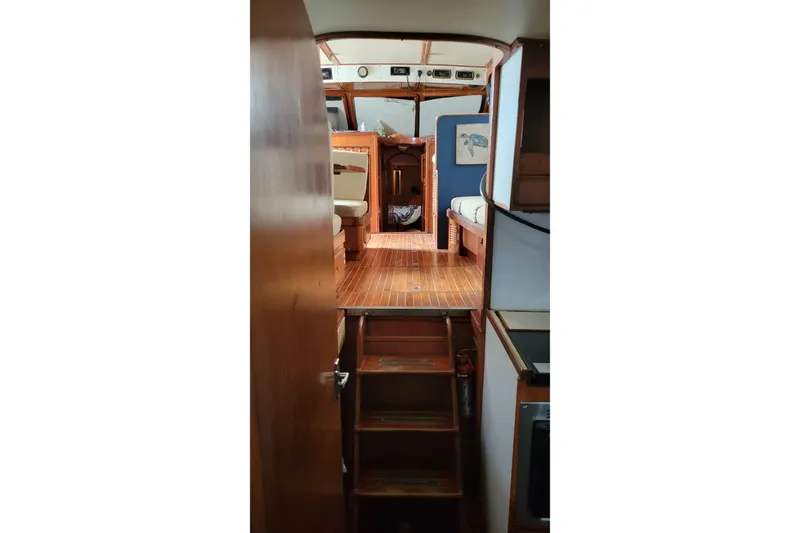 Slide: The Image of 1984 Kha Shing 40 Spindrift yacht interior with blue cushioned seating and marina view. - 11