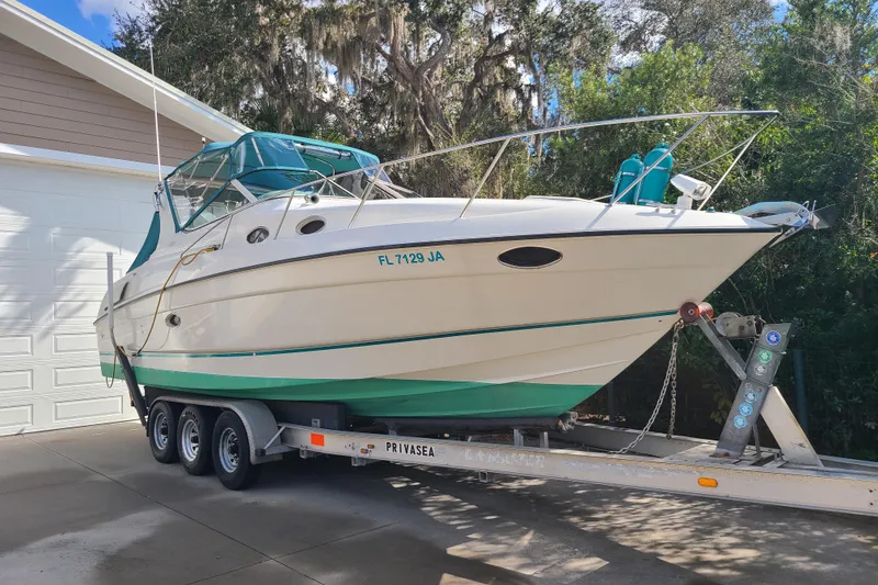 Slide: The Image of 1996 Regal Commodore 292 boat on trailer, parked in driveway, surrounded by trees. - 1