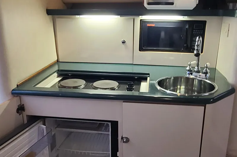 Slide: The Image of Compact kitchen in a 1996 Regal Commodore 292 boat with stove, sink, and microwave. - 10