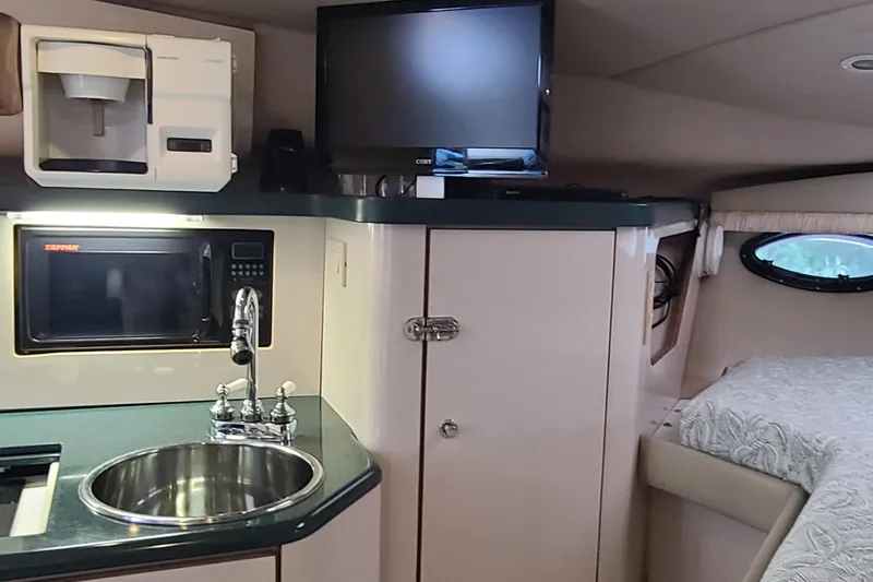 Slide: The Image of 1996 Regal Commodore 292 interior with kitchenette, sink, microwave, TV, and bed. - 11