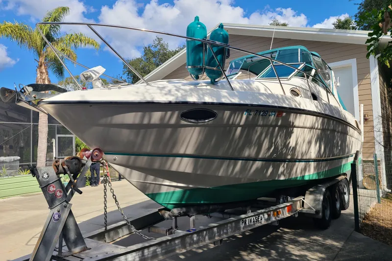 Slide: The Image of 1996 Regal Commodore 292 boat on trailer, parked outdoors under blue sky. - 2