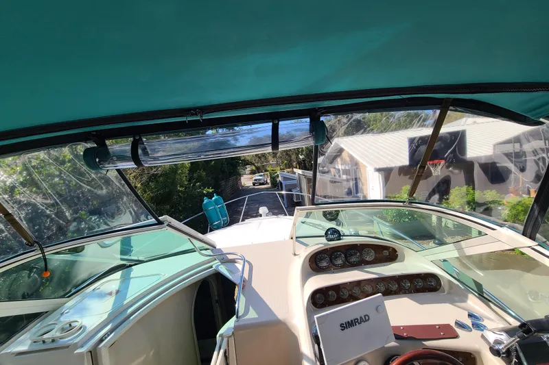 Slide: The Image of 1996 Regal Commodore 292 boat cockpit with dashboard and canopy, parked near a house. - 7