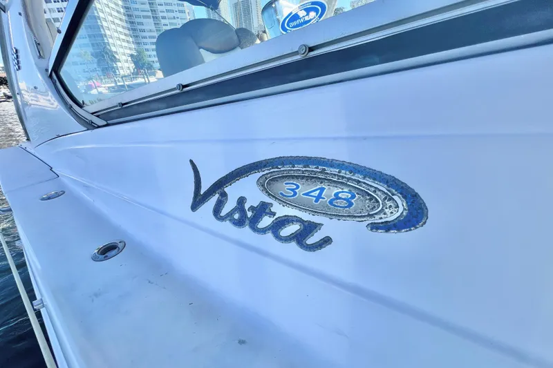 Slide: The Image of 2006 Four Winns 348 Vista boat exterior with logo, docked near cityscape. - 108