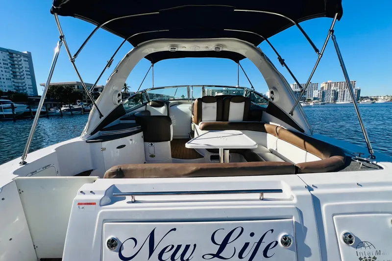 Slide: The Image of 2006 Four Winns 348 Vista boat interior with seating and table, docked by waterfront buildings. - 112