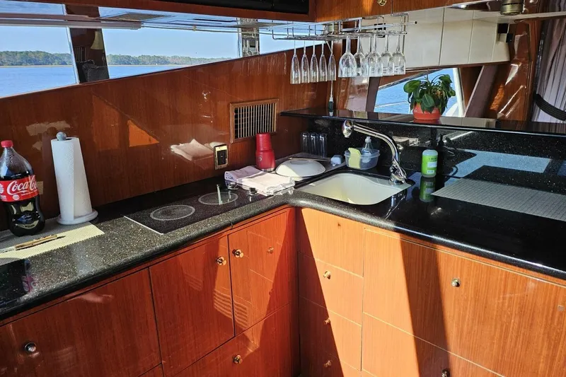Slide: The Image of Luxurious kitchen interior on a 2003 Johnson FLY yacht with wood cabinets and black countertops. - 21