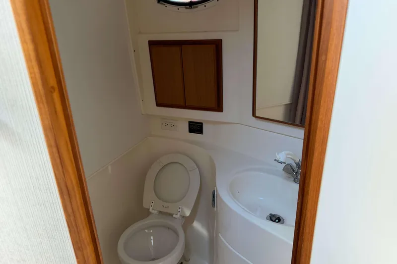 Slide: The Image of 2008 Henriques 30 Express boat bathroom with toilet, sink, and wooden cabinet. - 68