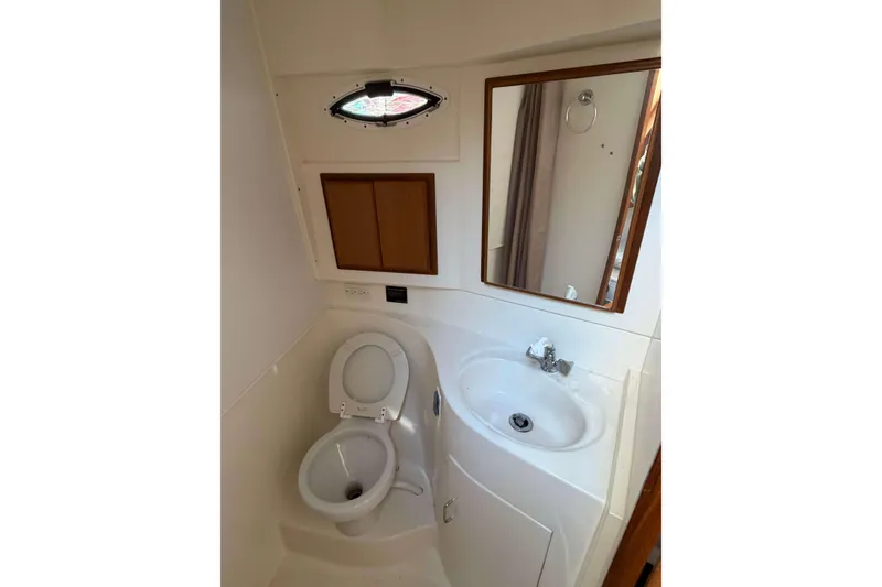 Slide: The Image of 2008 Henriques 30 Express boat bathroom with toilet, sink, mirror, and storage cabinet. - 69