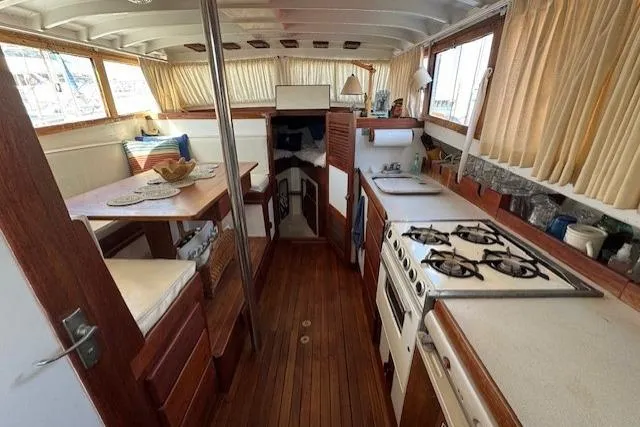 Slide: The Image of Interior of 1980 Roughwater MOTOR SAILER with kitchen and dining area, wooden flooring. - 11