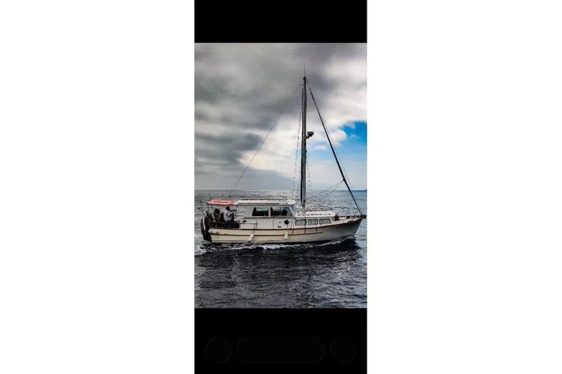Slide: The Image of 1980 Roughwater MOTOR SAILER cruising on open sea under cloudy skies. - 2
