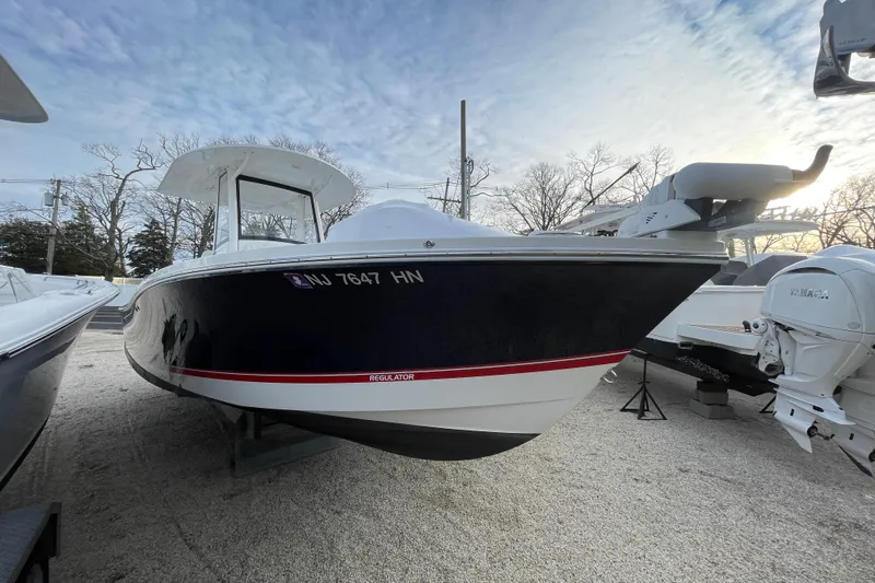 The Image of 2020 Regulator 26XO boat with sleek design, parked on gravel under a cloudy sky. - 0