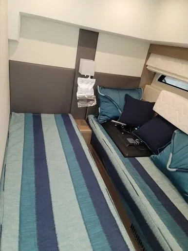 Slide: The Image of Interior of a 2016 Prestige 560 yacht with twin beds and blue stripes. - 30