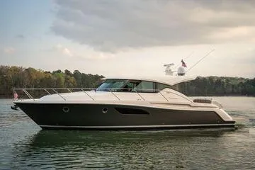 The Image of 2016 Tiara Yachts C44 Coupe cruising on a serene lake under a cloudy sky. - 0