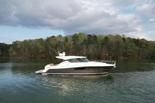 Slide: The Image of 2016 Tiara Yachts C44 Coupe cruising on a serene lake with forested backdrop. - 21