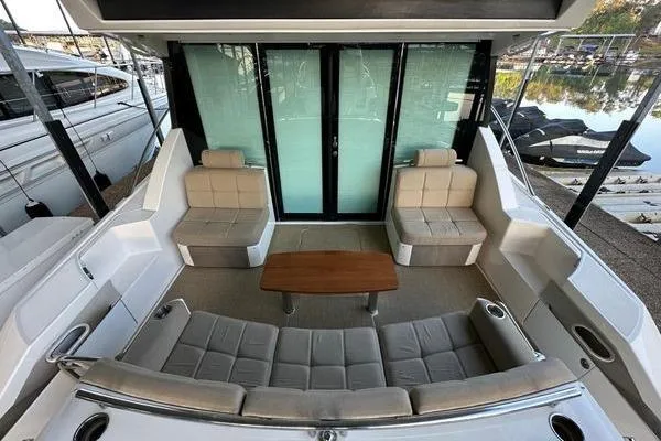Slide: The Image of 2016 Tiara Yachts C44 Coupe cockpit with plush seating and wooden table. - 4