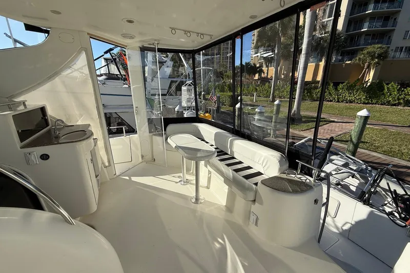 Slide: The Image of 2005 Meridian 459 Motoryacht interior with seating, table, and kitchenette, docked near greenery. - 8