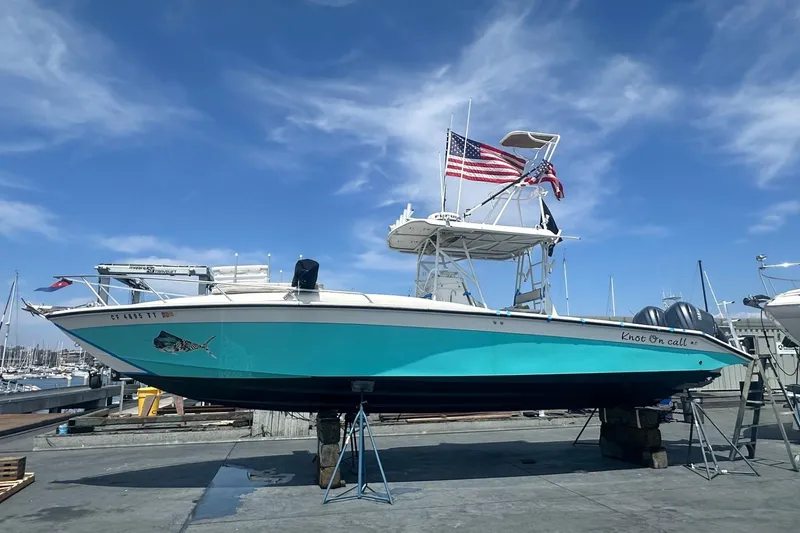 Slide: The Image of 1997 Marlin Yachts 350SF boat on dry dock with American flag, blue hull, and clear sky. - 21