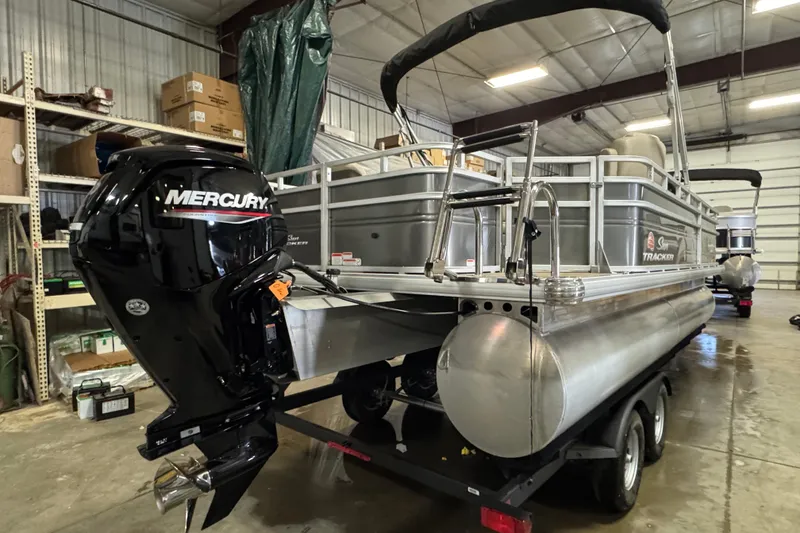 Slide: The Image of 2024 Sun Tracker Fishin' Barge 20 DLX pontoon boat with Mercury outboard motor in a warehouse. - 5