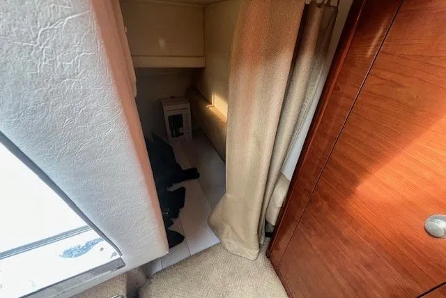 Slide: The Image of Interior cabin view of a 2006 Sea Ray Sundancer 260 boat, featuring wood paneling and curtains. - 25