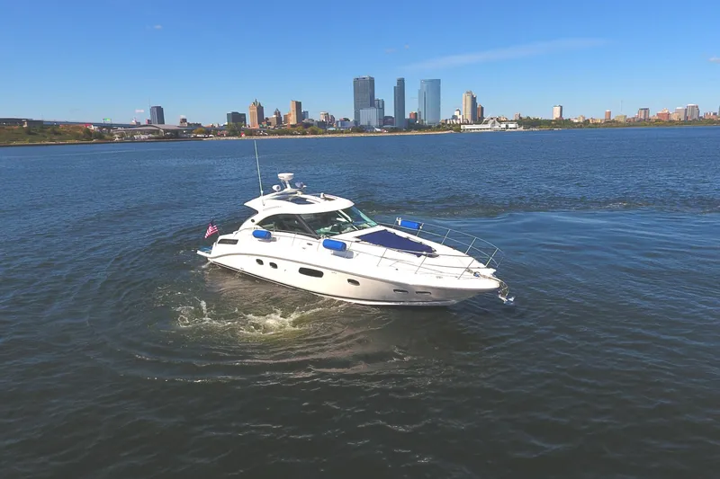 Slide: The Image of 2011 Sea Ray 470 Sundancer yacht cruising on a sunny day with city skyline backdrop. - 5