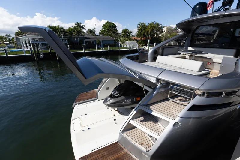 Slide: The Image of 2016 Pershing 62 yacht with open garage and sleek design, docked by waterfront homes. - 31