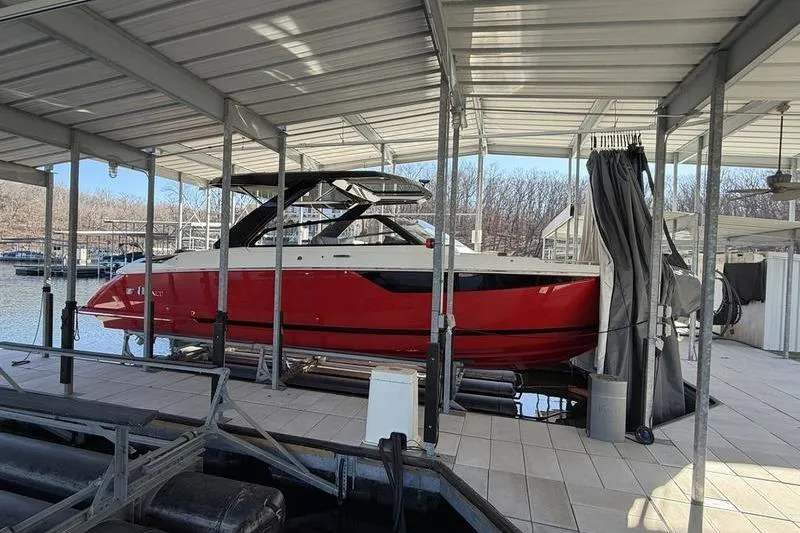 The Image of 2025 Cobalt R35 boat in a covered dock, featuring a sleek red and white design. - 1