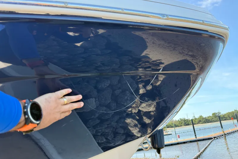 Slide: The Image of 2018 Hurricane SunDeck 2486 OB with visible hull scratches near a marina. - 4