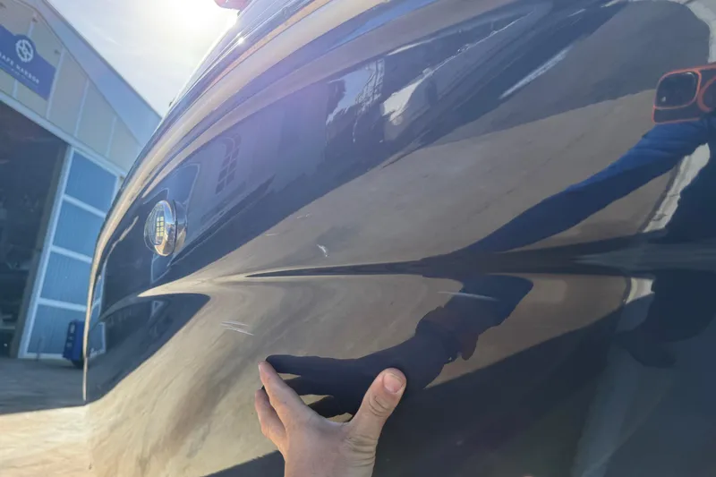 Slide: The Image of 2018 Hurricane SunDeck 2486 OB boat hull with minor scratches, hand inspecting surface. - 5